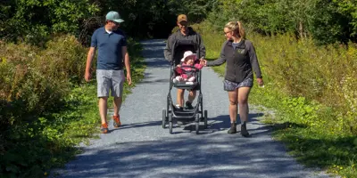 People walking on gravel trail pushing baby stroller.