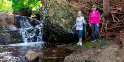 Two females standing beside waterfall on qplex trail.