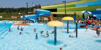 People swimming in pool and playing under water spray features.