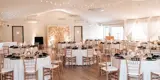 Event area decorated for wedding with head table and rounds of tables.