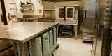 Kitchen with commercial fridge, stove, plates.
