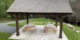 Open air picnic shelter with roof and 2 picnic tables.