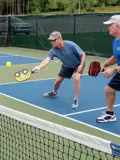 Man and partner hitting pickleball with paddle.